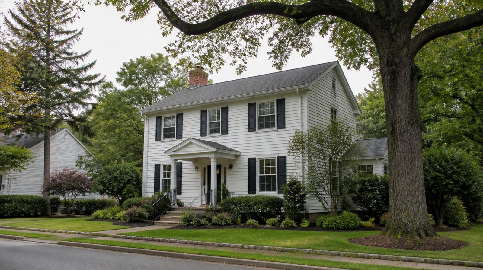 A white two-story colonial house on a tree-lined street in Middlesex County